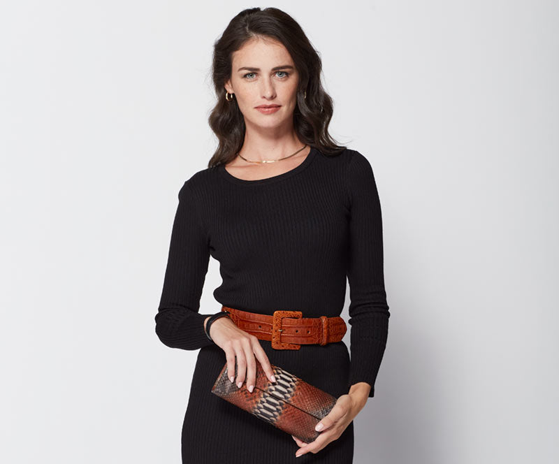 Female model wearing Glazed Alligator Belt with Covered Buckle holding Python Classic Clutch Handbag